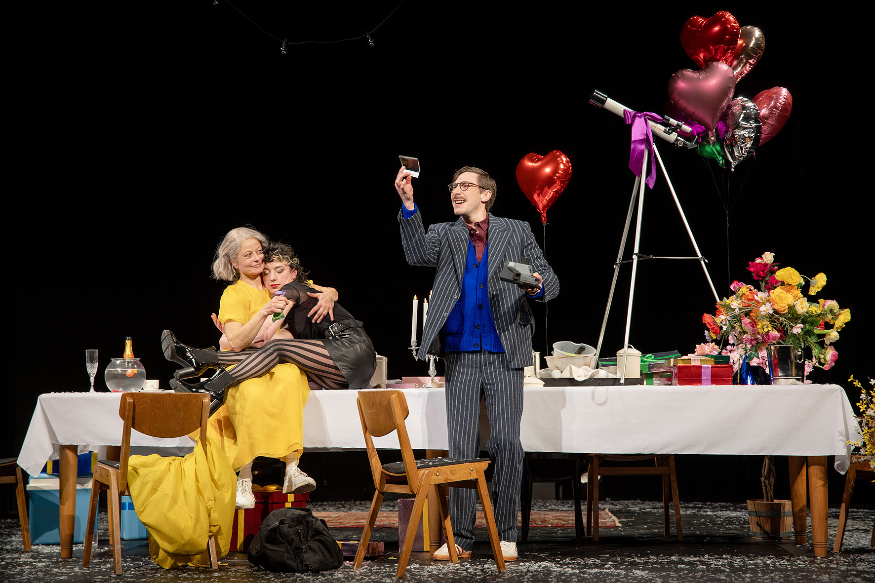 Schauspielszene aus Birthday Candles: Eine Figur sitzt nachdenklich an einem Tisch, warmes Licht und intime Bühnenatmosphäre.