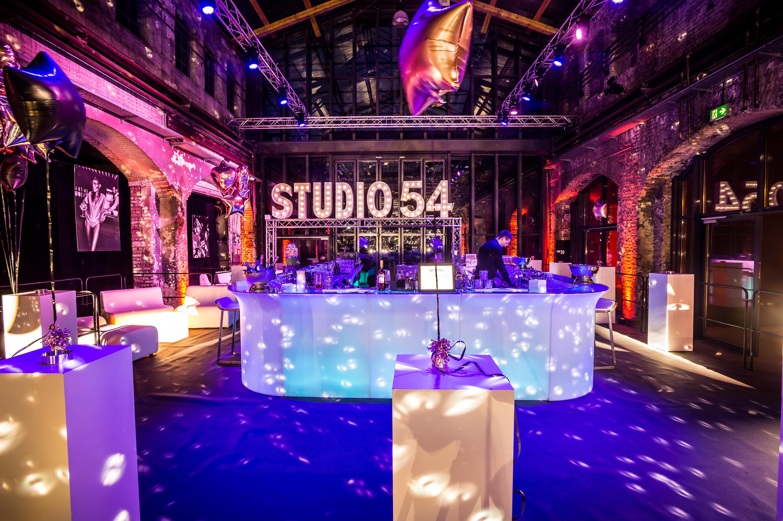 Stilvoll dekorierte Eventlocation im Werftquartier Lübeck mit leuchtender Bar und Studio-54-Thema.
